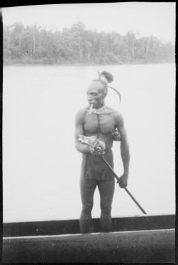 Man smoking whilst paddling a canoe, Ramu River, New Guinea, 1935 / Sarah Chinnery