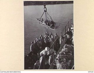 JAPANESE WOUNDED BEING HOISTED FROM A BARGE TO THE DECK OF THE DEBORAH IN A "STOKES LITTER" DURING THEIR EVACUATION FROM NUMA NUMA TO TOROKINA. THE EVACUATION FOLLOWS THE ARRIVAL AT NUMA NUMA ..