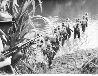 ALEXISHAFEN, NEW GUINEA. 1944-05-16. NX142396 PRIVATE A.C. SHERIDAN, (WITH THE BREN GUN AT THE FOREGROUND), GIVES COVERING FIRE TO MEMBERS OF A SECTION FROM NO. 14 PLATOON, C COMPANY, 35TH INFANTRY ..