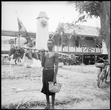 Man carrying a pole of plaited baskets, Rabaul, New Guinea, ca. 1936 / Sarah Chinnery