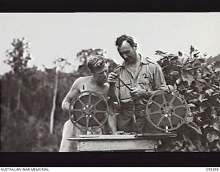 WAU, NEW GUINEA. 1943-08-9-12. FIELD OPERATORS OF THE AUSTRALIAN ARMY EDUCATION SERVICE FILM UNIT, PRIVATE J. RENNIE (LEFT) AND CORPORAL M. LEVI (RIGHT) REWIND AND SPLICE MOVIE FILM