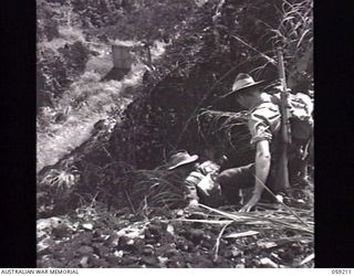 LALOKI VALLEY, NEW GUINEA. 1943-11-05. MEMBERS OF A PATROL FROM THE NEW GUINEA FORCE TRAINING SCHOOL (JUNGLE WING) SLIDING DOWN THE ROCKS NEAR THE ROUNA FALLS