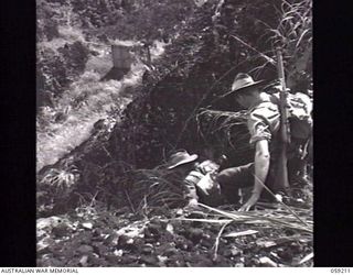 LALOKI VALLEY, NEW GUINEA. 1943-11-05. MEMBERS OF A PATROL FROM THE NEW GUINEA FORCE TRAINING SCHOOL (JUNGLE WING) SLIDING DOWN THE ROCKS NEAR THE ROUNA FALLS
