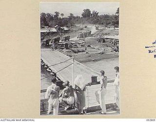 LAE, NEW GUINEA. 1945-06-09. PATIENTS WITH AN AUSTRALIAN ARMY NURSING SERVICE SISTER ON BOARD THE HOSPITAL SHIP MANUNDA WATCHING AMBULANCES OF 2/7 GENERAL HOSPITAL BRINGING OTHER PATIENTS TO THE ..