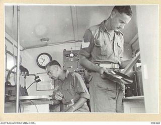 WEWAK, NEW GUINEA. 1945-10-29. SERGEANT E.C. PARRANT (1) AND SERGEANT N.S. BRAY (2), MEMBERS OF 1 BROADCASTING STATION, AUSTRALIAN ARMY AMENITIES SERVICE WORKING AT RADIO STATION 9AJ DURING A ..