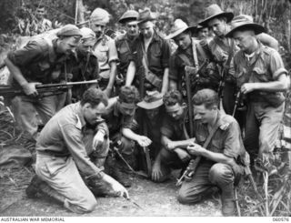 SATTELBERG AREA, NEW GUINEA. 1943-11-15. A PATROL FROM C COMPANY, 2/24TH AUSTRALIAN INFANTRY BATTALION, SETTING OUT TO TAP A JAPANESE TELEPHONE WIRE, BEING BRIEFED BY THE OFFICER COMMANDING C ..