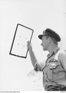 NADZAB, NEW GUINEA. C. 1944-02. FLYING OFFICER G. L. STEVENSON, NEWCASTLE, NSW, OF NO. 24 VULTEE VENGEANCE SQUADRON RAAF, HOLDING UP HIS GLASS WINDSCREEN THAT WAS HIT BY LIGHT ACK ACK FIRE OVER ..