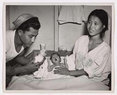 Photograph of Coast Guardsman Attempting to Amuse an Infant with a Rubber Doll