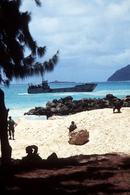 Marines take up positions on the beach at Bellows Air Force Station during an amphibious assault exercise. A utility landing craft is just off the beach