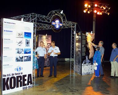 Military members along with Korean War veterans observe the displays provided during the Korean War Symposium reception held at Hickam AFB, Hawaii