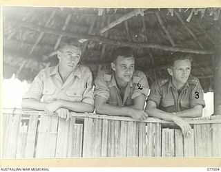 JACQUINOT BAY, NEW BRITAIN. 1944-11-18. THREE PATROL OFFICERS OF THE AUSTRALIAN NEW GUINEA ADMINISTRATIVE UNIT RELAXING IN THEIR HUT AT THE MALMAL VILLAGE. IDENTIFIED PERSONNEL ARE:- NX154774 ..