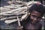 Young boy carries bundle of firewood