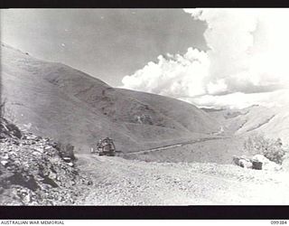 WAU-LABU ROAD, NEW GUINEA, 1945-12-13. A SECTION OF THE ROAD SKIRTING THE HILLS ALONG THE SNAKE RIVER. A 10-FOOT DRAWN GRADER TOWED BY A HD7 TRACTOR OF 8 MECHANICAL EQUIPMENT COMPANY IS AT WORK AT ..