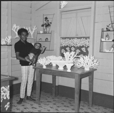 A young woman holding a baby next to a table of coral, Isle of Pines, New Caledonia, 1967 / Michael Terry