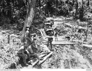 SORAKEN AREA, BOUGAINVILLE. 1945-06-07. NATIVES REPAIRING A BRIDGE AND CORDUROY TRACK LEADING UP TO FORWARD COMPANYS FROM 31/51 INFANTRY BATTALION TACTICAL HEADQUARTERS. IN THE FOREGROUND VISITING ..