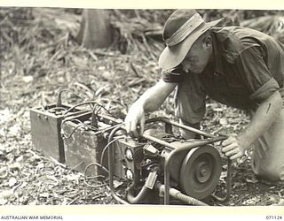 KILIGIA, NEW GUINEA. 1944-03-12. QX57857 SIGNALMAN J.V. DAVIDSON (1) OF HEADQUARTERS, 5TH DIVISION SIGNALS, OPERATING AN AC/DC 250 WATT "PIONEER" CHARGING SET USED FOR CHARGING BATTERIES IN THE ..