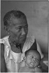 Elderly woman, Bomtavau, holding young infant, perhaps her grandchild