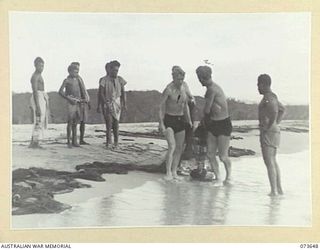 SALAMAUA, NEW GUINEA. 1944-06-01. MEMBERS OF THE 2ND MARINE FOOD SUPPLY PLATOON ASSISTED BY NATIVES FROM A NEARBY VILLAGE USE A DRAGNET CONTAINING FISH TO CARRY THE CATCH TO A DINGHY WHERE THEY ..