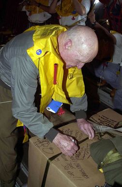 On board a US Air Force (USAF) C-130 Hercules from Yokota Air Base (AB), Japan, retired USAF Colonel (COL) Gail Halvorsen, the Candy Bomber, writes a holiday greeting on a box of supplies to be dropped during the first flight of the 50th anniversary flights called the Christmas Drop on Dec. 21 2002