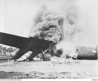 MILNE BAY, 1942-08-27. AN AMERICAN LIBERATOR AIRCRAFT (B24) WHICH MADE A FORCED LANDING AT MILNE BAY IS SET ON FIRE BY JAPANESE DIVE BOMBERS. (D. BRAUND COLLECTION)