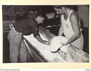 YALU, NEW GUINEA. 1945-08-03. STUDENTS MIXING DOUGH IN THE BAKING WING OF THE NEW GUINEA TRAINING SCHOOL. IDENTIFIED PERSONNEL ARE:- CORPORAL S.A. REID (1); PRIVATE R.W. BAKER (2)