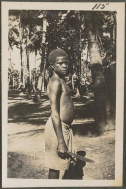 Papuan boy in a sarong with a knife, New Britain Island, New Guinea, probably 1916