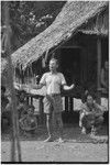 Meeting: man speaks in front of gathered crowd, gestures with his arms