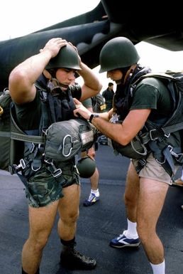A1C Corley, a member of the combat control team, has his parachute straps checked by CAPT Busby, also of the CCT