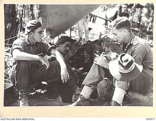 BOUGAINVILLE, 1945-07-14. LIEUTENANT T. FARRELL, PUBLIC RELATIONS OFFICER 93), LISTENS WHILE STAFF-SERGEANT L.T. LEA (1), AND WARRANT OFFICER 2 F.W. RANKIN (2), MEMBERS OF D COMPANY, 15 INFANTRY ..