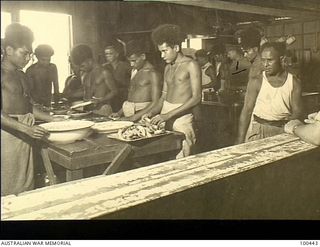 Ela Beach, New Guinea. 1944-05-10. Warrant Officer Hadaway (third from right), Catering Corps instructor, watching native cooking staff preparing meals in the kitchen of the Officers Club