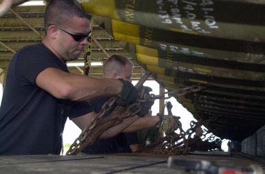 US Air Force (USAF) Airmen assigned to the 7th Expeditionary Munitions Squadron uses tie down chains to secure a load of Mark 82 500-pound general purpose bombs to a munitions trailer at Andersen Air Force Base, Guam, during Operation IRAQI FREEDOM