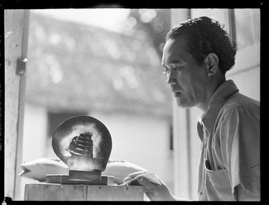Unidentified local man with a ship carved on a shell, includes a carved fish, Rarotonga, Cook Islands