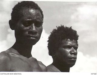 SALAMUA, NEW GUINEA. 1943-09-20. TWO NATIVE LABOURERS. THE ONE ON THE LEFT HAS BEEN IN JAPANESE HANDS AND THE ONE ON THE RIGHT HAS BEEN WORKING FOR THE AUSTRALIAN NEW GUINEA ADMINISTRATIVE UNIT. ..