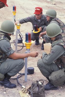 An instructor from Detachment 1, 554th Civil Engineering Squadron, Heavy Repair, discusses assembly of airfield lights with members of the Guam Air National Guard during a Prime Base Engineer Emergency Force and Prime Readiness in Base Services group-coordination exercise. The exercise is designed to consolidate the skills of civil engineering and services groups into a single unit capable of deploying to areas in need of emergency aid