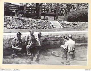 LAE AREA, NEW GUINEA. 1945-07-29. PRIVATE I. LOHNEYER, 2/7 ADVANCED WORKSHOP (4), BEING BAPTISED BY CHAPLAIN A.H. ORR (5), AT HEADQUARTERS LAE BASE SUB-AREA. IDENTIFIED PERSONNEL ARE:- PRIVATE R. ..