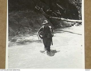 FARIA RIVER, RAMU VALLEY, NEW GUINEA. 1944-01-18. QX28819 GUNNER E. D. HIRST OF THE 2/4TH FIELD REGIMENT FORDING THE FAST FLOWING FARIA RIVER ON HIS WAY TO THE FORWARD POSITIONS