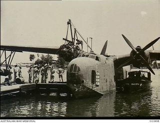 MADANG, NEW GUINEA. 1945-01-15. THE STARBOARD ENGINE OF A MARTIN MARINER FLYING BOAT AIRCRAFT, A70-8 VHCPH, OF NO. 41 SQUADRON RAAF, IS CHANGED ALONGSIDE A JETTY. FITTINGS ARE PROVIDED ON THE WING ..