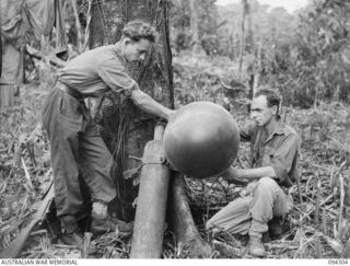 MAMAGOTA AREA, BOUGAINVILLE. 1945-07-22. GUNNER J.E. GARDINER (1) AND GUNNER J.E. TURNBULL (2) MEMBERS OF 3 SURVEY BATTERY, ROYAL AUSTRALIAN ARTILLERY, FILLING A BALLOON WITH HYDROGEN FROM ..