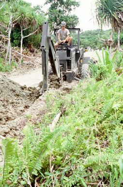 Equipment Operator 2nd Class Emil A. Norby uses a backhoe to dig a waterline on the island of Yap. Norby, a U.S. Navy construction battalion member, is part of a Civic Action Team deployed to the island to aid villagers with construction projects and offer vocational training