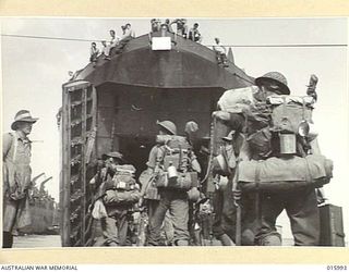 1943-10-27. NEW GUINEA. LANDING OPERATIONS. AUSTRALIANS EMBARKING THROUGH THE BOWS OF A BEACH LANDING SHIP, FROM WHICH THEY DISEMBARKED NORTH WEST OF LAE, AND SEVERED ITS COMMUNICATIONS WITH ENEMY ..