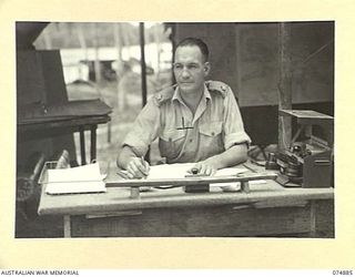 MILILAT, NEW GUINEA. 1944-07-22. NX102722 MAJOR K.J. WOOD, OFFICER COMMANDING, 5TH SURVEY BATTERY, AT HIS DESK IN HIS TENT OFFICE