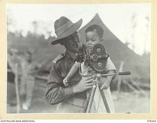 TOROKINA, BOUGAINVILLE ISLAND, 1945-01-05. NX162393 LIEUTENANT D. KINNA, MILITARY HISTORY SECTION SHOWING ONE OF THE CHINESE REFUGEE CHILDREN HIS CAMERA. THIS CHILD IS ONE OF THE 25 CHINESE THAT ..