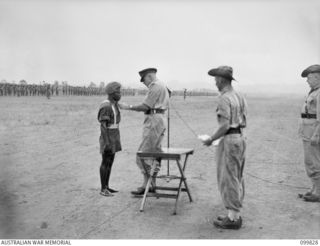 RABAUL, NEW BRITAIN, 1946-02-14. MAJOR GENERAL K.W EATHER, GENERAL OFFICER COMMANDING 11 DIVISION, PRESENTING THE MILITARY MEDAL TO PRIVATE SALA, 1 NEW GUINEA INFANTRY BATTALION, DURING A SPECIAL ..