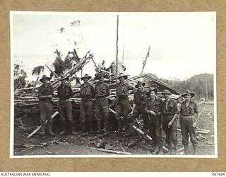 WAREO, NEW GUINEA. 1943-12. OFFICERS OF THE 2/3RD AUSTRALIAN INFANTRY BATTALION, GROUPED AROUND THE VICTORY FLAG. THIS FLAG WAS PREVIOUSLY RAISED OVER KOKODA, BUNA AND SATTELBERG. IDENTIFIED ..