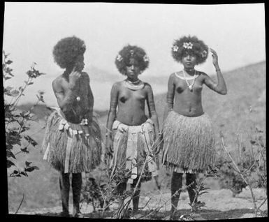 Three women wearing grass skirts, two with hands to their heads, Papua, ca. 1923 / Sarah Chinnery