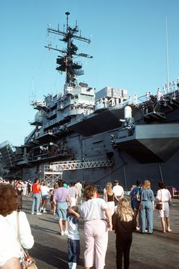 Family members and friends of crewmen aboard the amphibious assault ship USS GUAM (LPH-9) watch as the sailors depart for the Persian Gulf in support of Operation Desert Shield