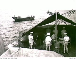 THE SOLOMON ISLANDS, 1945-08-20. OFF MOILA POINT, TWO JAPANESE OFFICERS UNDER NAVAL GUARD ON BOARD HMAS LITHGOW WAIT FOR SURRENDER ARRANGEMENTS TO BE DISCUSSED. NEARBY IS THE JAPANESE BARGE, FLYING ..