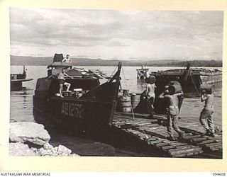 TOL PLANTATION, NEW BRITAIN, 1945-07-26. SAPPERS OF 53 PORT CRAFT COMPANY, LOADING STORES ON THE BARGE, AB1252 AT TOL WHARF. THE SUPPLIES ARE FOR THE AUSTRALIAN NEW GUINEA ADMINISTRATIVE UNIT CAMP ..
