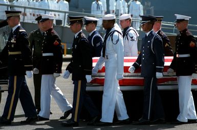 The flag-draped casket of the Unknown Serviceman of the Vietnam Era is placed on the pier by a joint service honor guard in preparation for a wreath-laying ceremony. The casket will be transported to California aboard the frigate USS BREWTON (FF 1086), and then transferred to Arlington National Cemetery for interment at the Tomb of the Unknowns