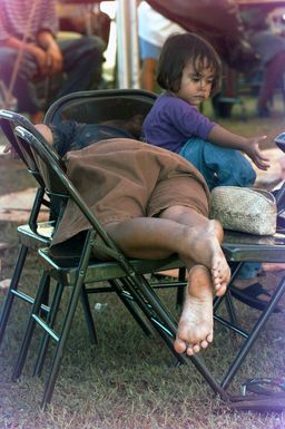 Napping helps pass the time for typhoon victims while waiting for a room assignment at the temporary housing in converted dorms at Andersen Air Force Base south, Guam, after Super Typhoon Paka destroyed or badly damaged their homes